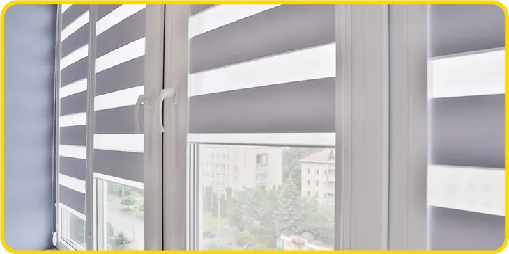 A close-up view of modern windows with white frames and zebra roller blinds, alternating transparent and opaque stripes, partially open to reveal a blurred cityscape outside—an elegant touch inspired by Gallery Central Florida Awnings.